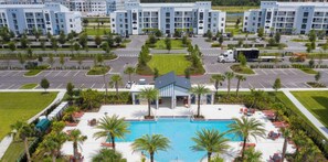 A hotel with a swimming pool, parking area, and a road with vehicles.