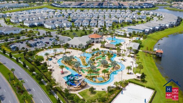 Vista aérea de una zona residencial con un gran complejo de piscinas, rodeado de casas unifamiliares y una masa de agua.