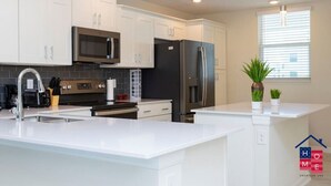 Una cocina moderna con armarios blancos, electrodomésticos de acero inoxidable y una isla central.