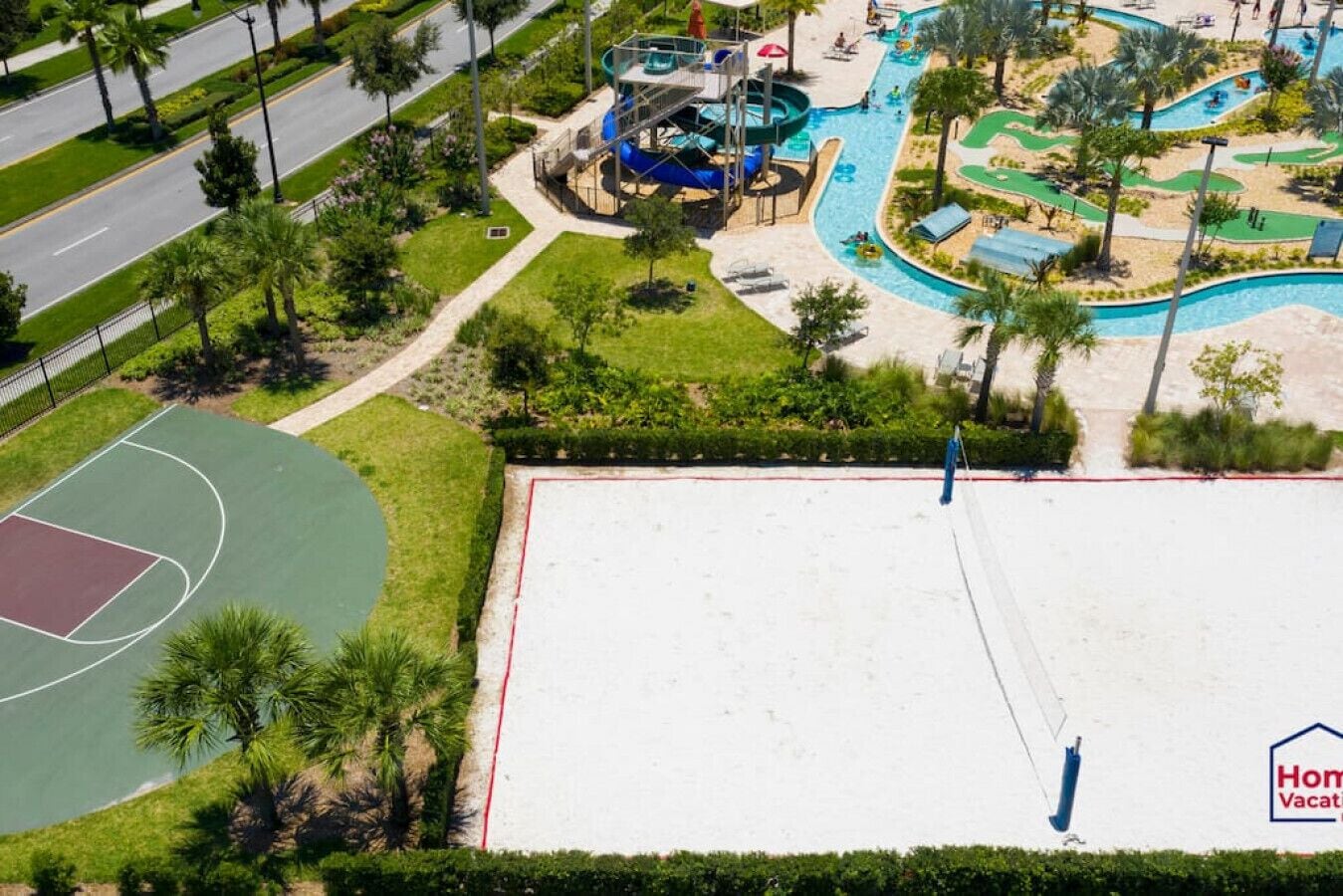 An aerial view of a resort with a swimming pool, water slides, and a basketball court.