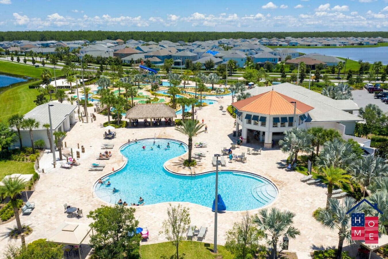 Un resort con piscina centrale, diverse camere per gli ospiti e vista su un lago.