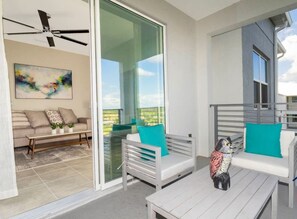 Un balcon moderne agrémenté d’un canapé, de chaises et d’une sculpture d’oiseau décorative.