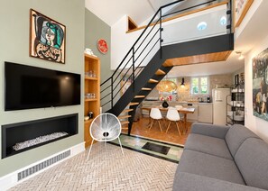 A modern living room with a grey sofa, a black TV, and a herringbone-patterned floor. - Charming renovated house 200m from beaches (Juan-les-Pins)