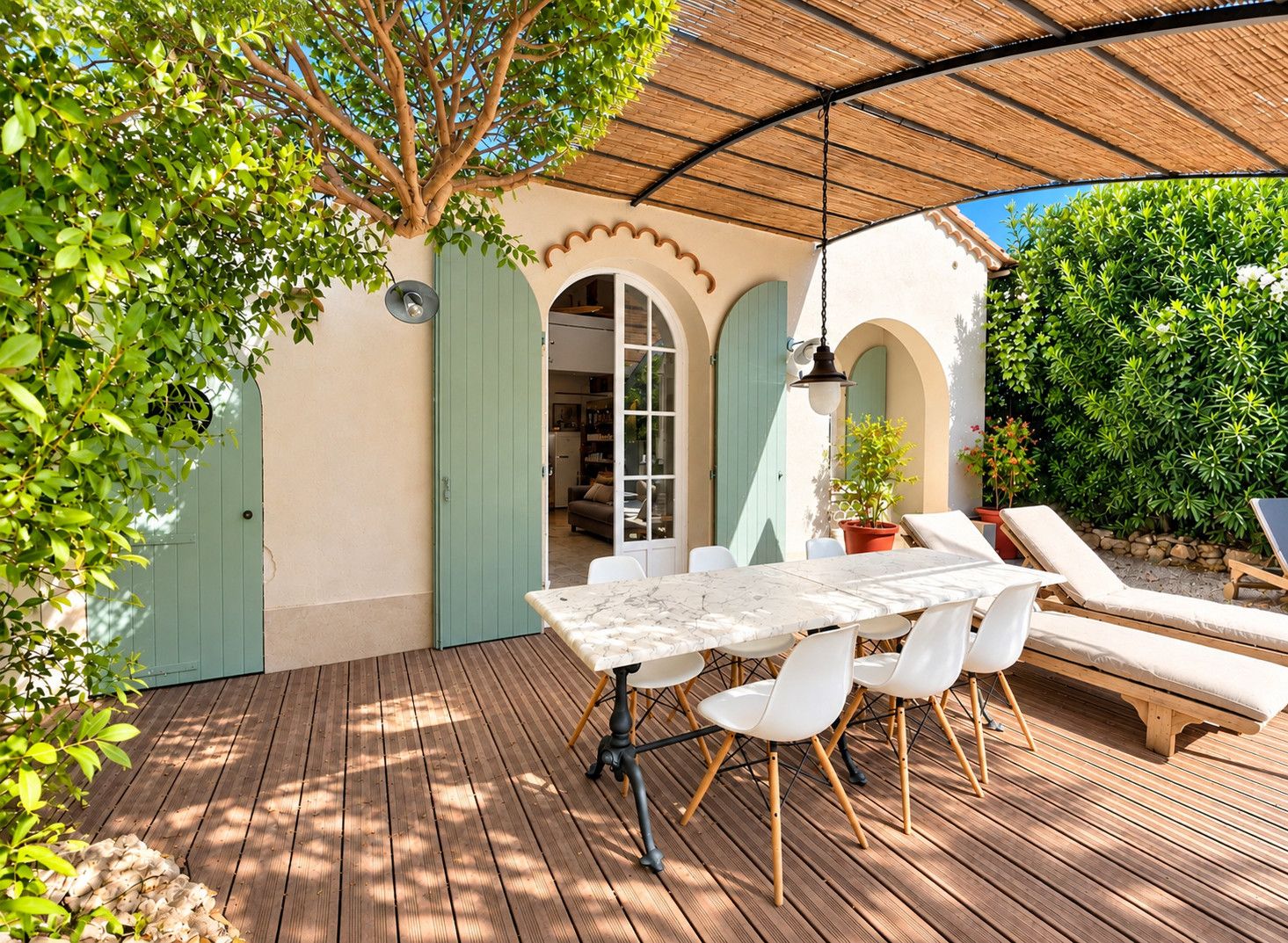 An outdoor patio with a table and chairs, a hanging light fixture, and a covered area with a thatched roof.