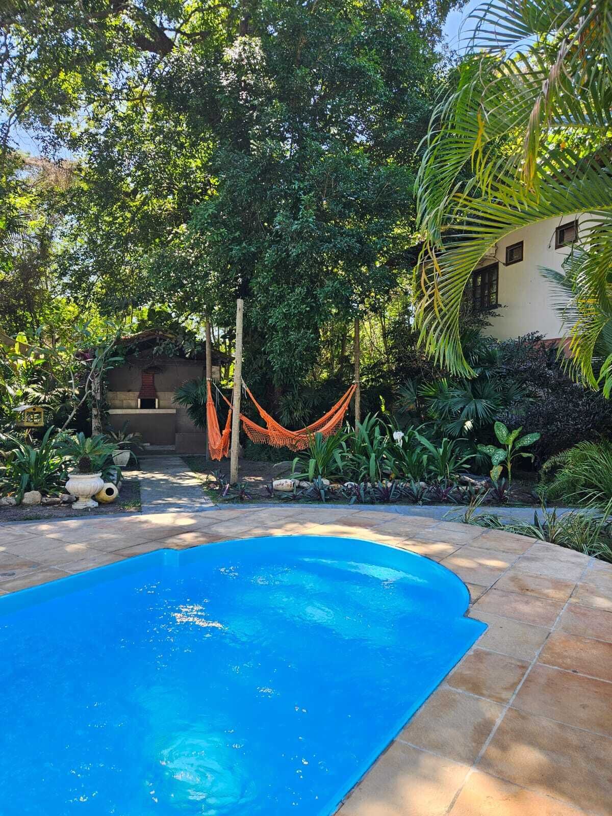 A swimming pool surrounded by lush greenery and a hammock.