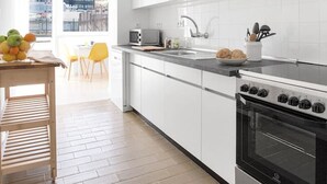 Una cocina moderna con armarios blancos, una estufa de acero inoxidable y un amplio ventanal con vistas a la ciudad.