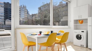 Una cocina moderna con comedor, ventanas amplias y lavadora.