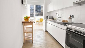 Una cocina moderna con armarios blancos, una estufa negra y una mesa de madera con fruta.