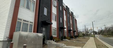 A row of modern townhouses with a concrete pathway and bollards.