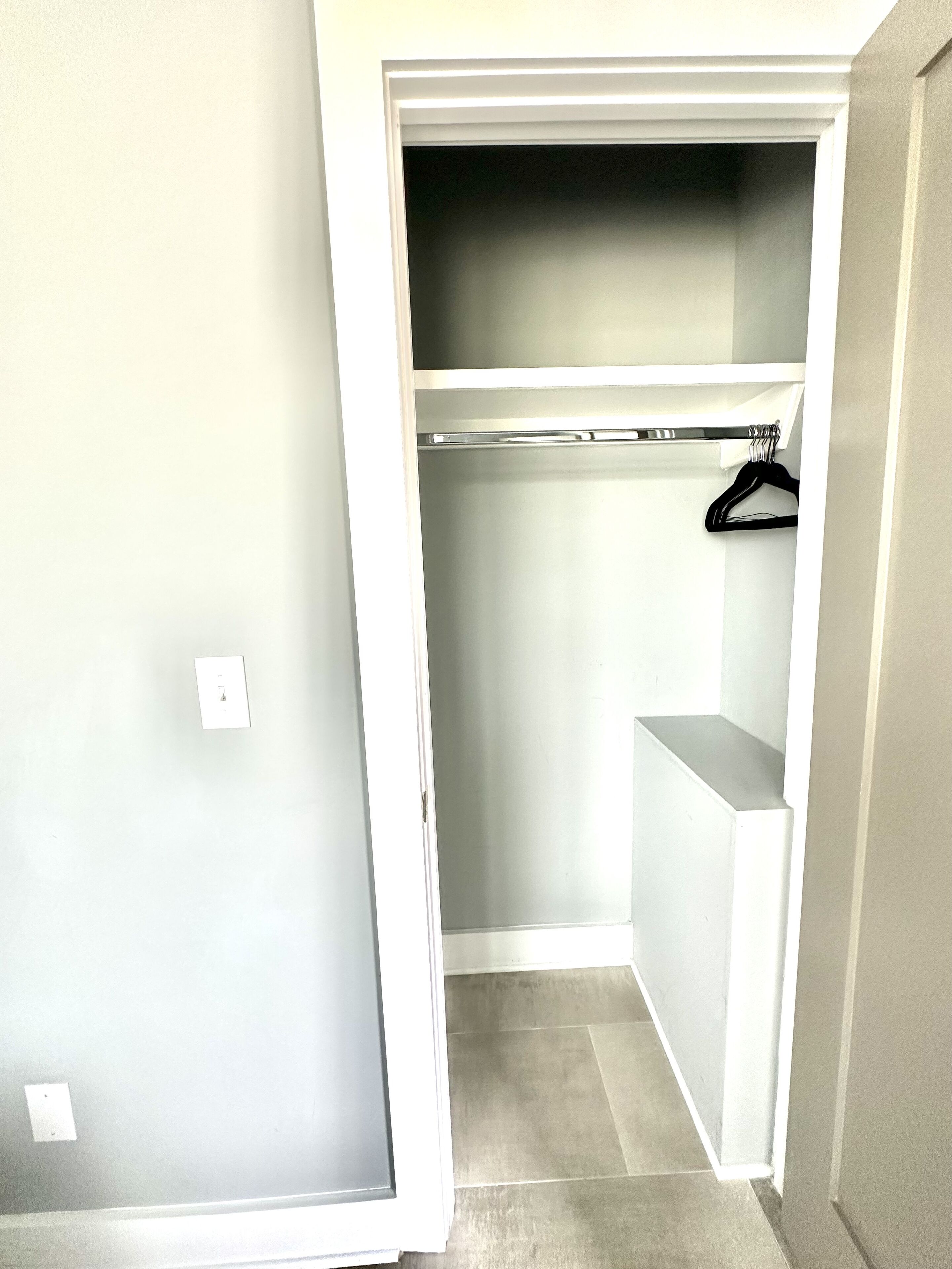 A walk-in closet with a hanging rod and a shelf.