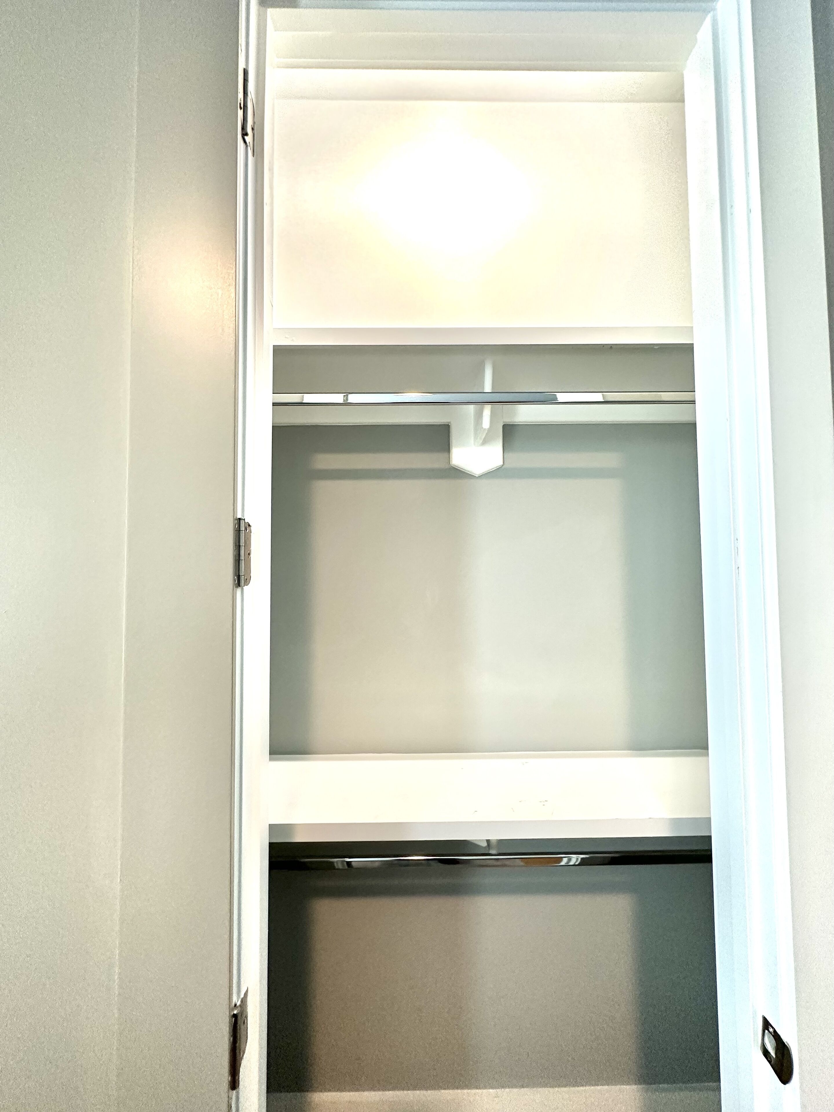 A view of a closet with hanging space and a shelf.