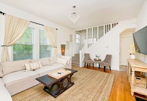 Relax in this stylish living room with a sofa, coffee table, and chandelier, offering a comfortable space to unwind.