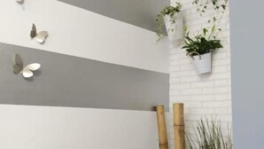 A room with a white brick wall, horizontal stripes, a hanging plant, and two bamboo sticks. - Duplex Sweet Home by SevillaLuxurySuites (Sevilla)