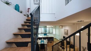 A staircase leading to a dining area with a kitchen in the background. - Duplex Sweet Home by SevillaLuxurySuites (Sevilla)