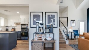 A modern kitchen with a central island, a dining area with a blue chair, and a staircase leading to another level. - Lakeside Paradise, lake views, hot tub (Canyon Lake)