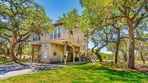 A two-story wooden house with a covered porch, surrounded by large trees. - Lakeside Paradise, lake views, hot tub (Canyon Lake)