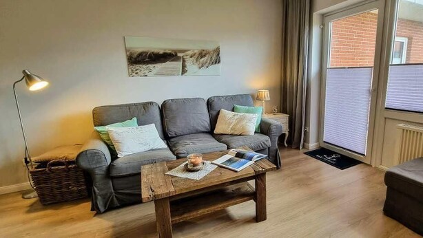 Ein Wohnzimmer mit grauem Sofa, einem Holztisch und einer Lampe.