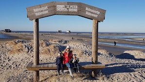 Un cartello in legno con indicazioni per località come 'Nationalpark Waddenmeer' e 'St. Peter-Ording'.