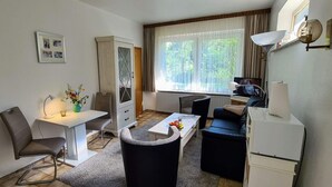Un ambiente compatto con un tavolo da pranzo, una poltrona letto, un mobiletto e una televisione.