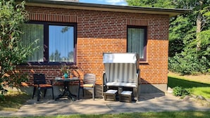 Una casa in mattoni con un patio che include un tavolo, due sedie e un piccolo divano.