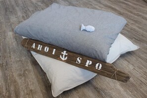 Ein Kissen mit einem fischförmigen Anhänger und einem Holzschild mit dem Aufdruck "Ahoit spO".