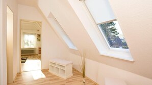 A room with a sloped ceiling, a skylight, a white bench, and a radiator. - Haushälfte "kuddel" 104 (St. Peter-Ording)
