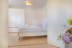 Un dormitorio minimalista con cama, mesita de noche y espejo.