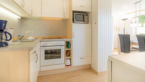 A compact kitchen with a built-in microwave, oven, and a coffee maker on the counter. - Wohnung A (St. Peter-Ording)