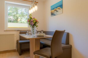 Un comedor con una mesa dispuesta para dos personas, un florero y un cuadro en la pared.