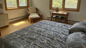 Una camera da letto con un letto, una sedia, un tavolo e due finestre.