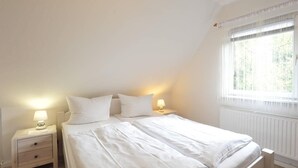 Ein Schlafzimmer mit einem Bett, zwei Nachttischen und einem Fenster mit Vorhängen.