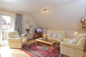 A living room with a sofa set, a coffee table, a television, and a patterned rug. - Fewo Dünenblick Ii-whg. 5 (St. Peter-Ording)