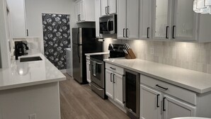 A modern kitchen with white cabinetry, stainless steel appliances, and a black refrigerator. - Boutique Condo in North Scottsdale (Scottsdale)