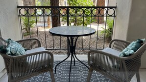 A balcony with wicker chairs and a round table, surrounded by a metal railing. - Boutique Condo in North Scottsdale (Scottsdale)