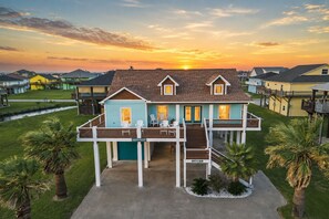 Une maison à deux étages avec un porche abrité, une petite terrasse et une vue sur le coucher du soleil.
