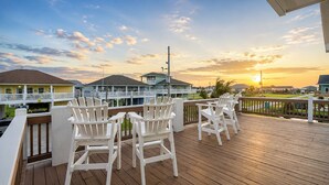 A wooden deck with white chairs and a view of houses in the background.