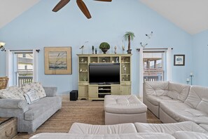 Relax in this stylish living room with a high ceiling, flat-screen TV, and comfortable seating areas.