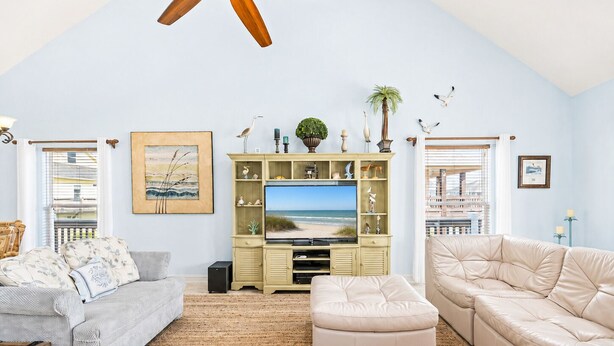 A living room with a television, two sofas, a coffee table, and decorative items.