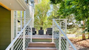 Una terraza de madera con barandas blancas que conduce a la entrada de una casa.