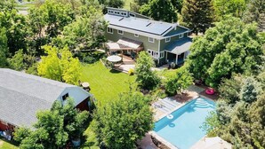 Una casa grande con piscina, rodeada de árboles y un césped cuidado.