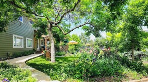 A house with a front porch, a lawn, and various plants and flowers. - La Casita Colorado - Sleeps 4 People (Longmont)
