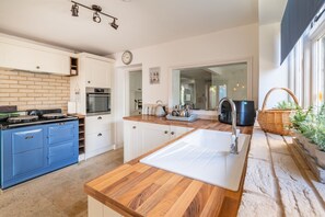 A modern kitchen with a blue stove, white cabinets, and a wooden countertop. - Homestead, Southrepps, Norfolk (Southrepps)