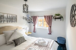 A neatly arranged bedroom with a bed, bedside table, and a wall-mounted shelf with plants.