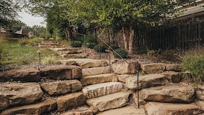 A stone staircase leading up to a wooden deck with a metal railing. - SLICE OF HEAVEN lake front cottage with HOTTUB, fire pit, kayaks & Dog friendly! (Akron)