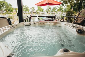 A hot tub with a view of a lake and houses in the background. - SLICE OF HEAVEN lake front cottage with HOTTUB, fire pit, kayaks & Dog friendly! (Akron)