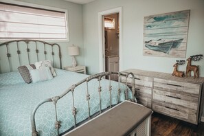 A bedroom with a bed, dresser, and artwork. - SLICE OF HEAVEN lake front cottage with HOTTUB, fire pit, kayaks & Dog friendly! (Akron)