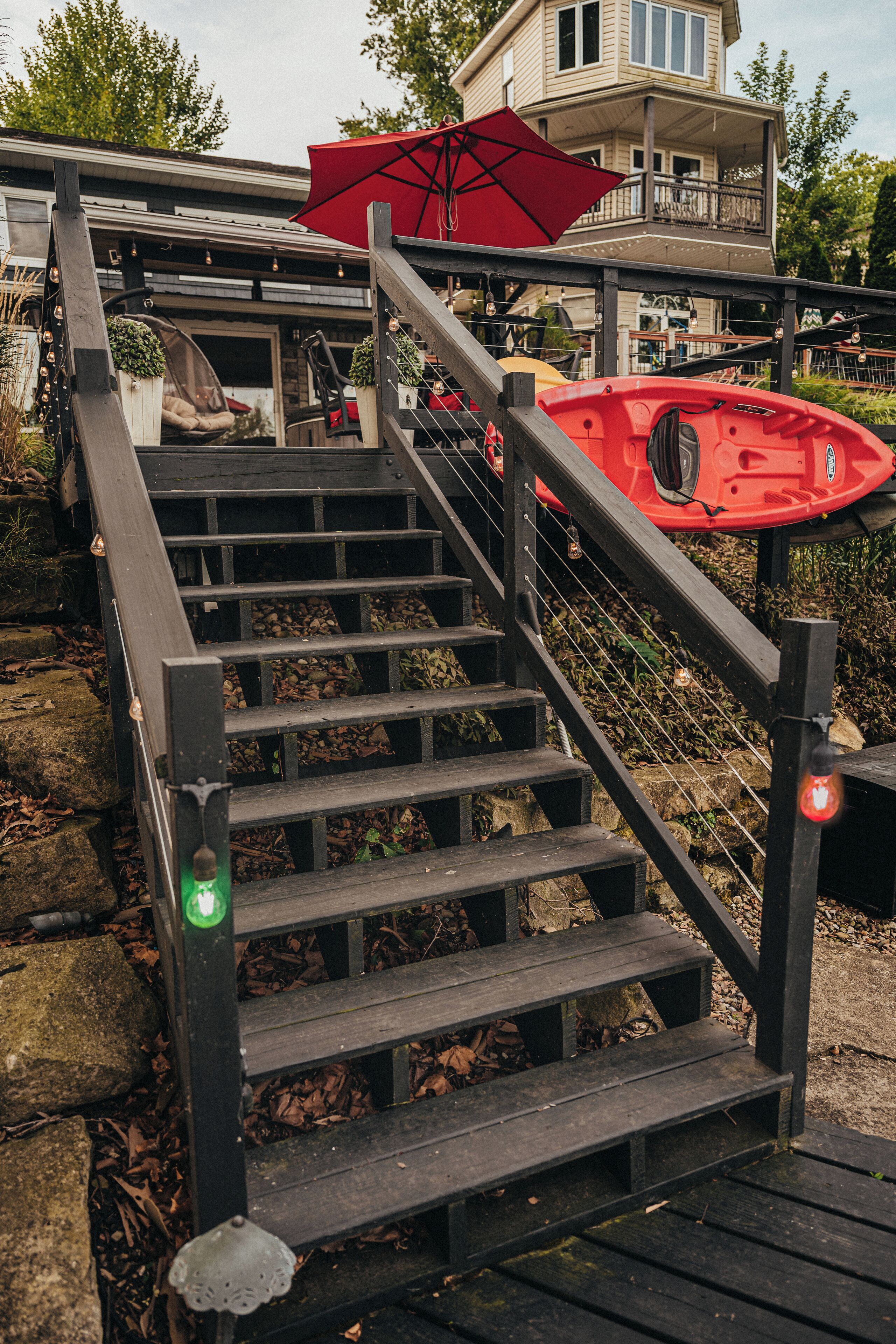 Una escalera de madera con un kayak rojo y un paraguas en la plataforma.