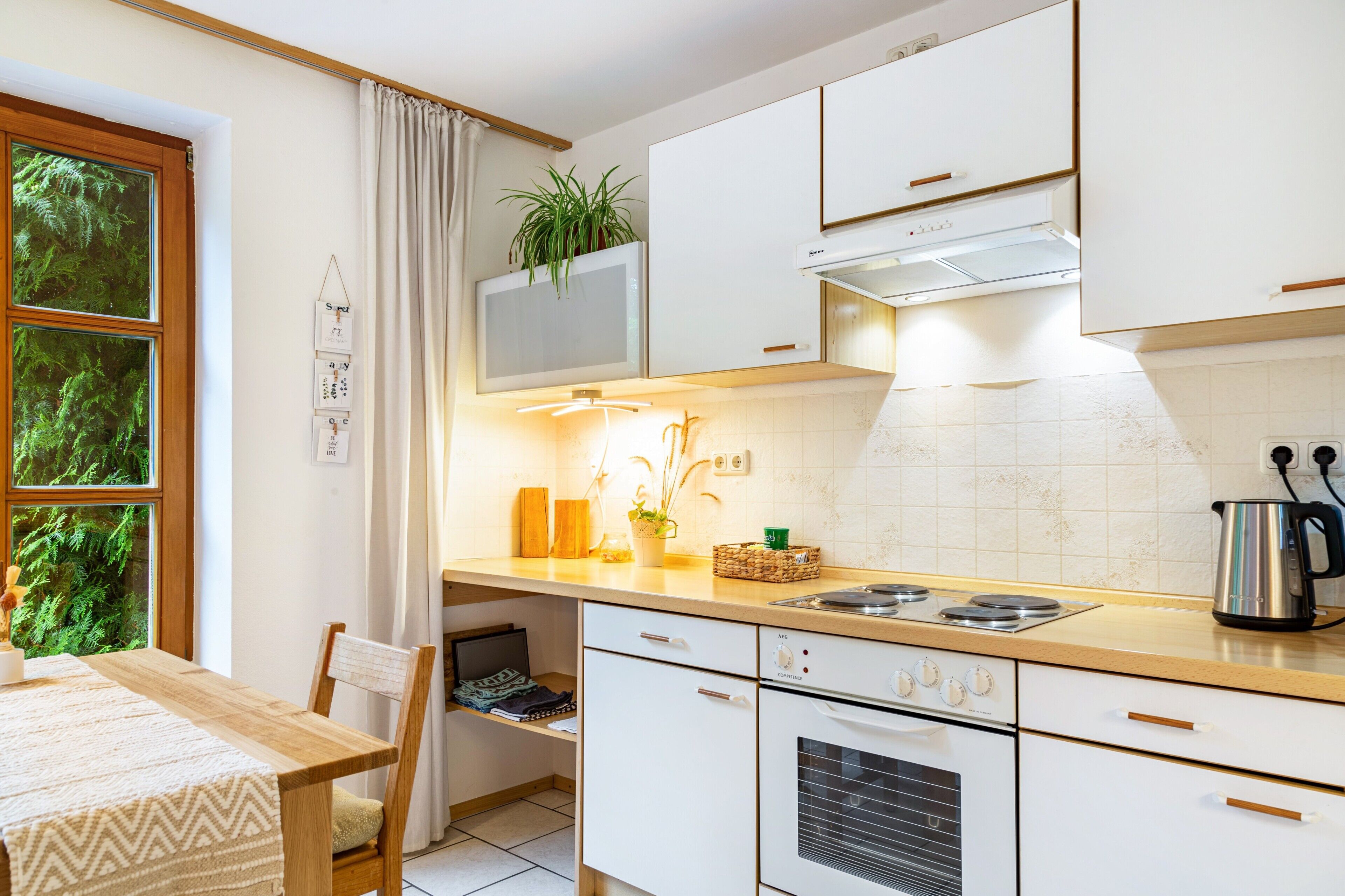 A kitchen with white cabinets, a stove, a sink, and a window with curtains.