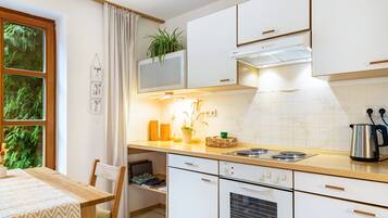 A kitchen with white cabinets, a stove, a sink, and a window with curtains.
