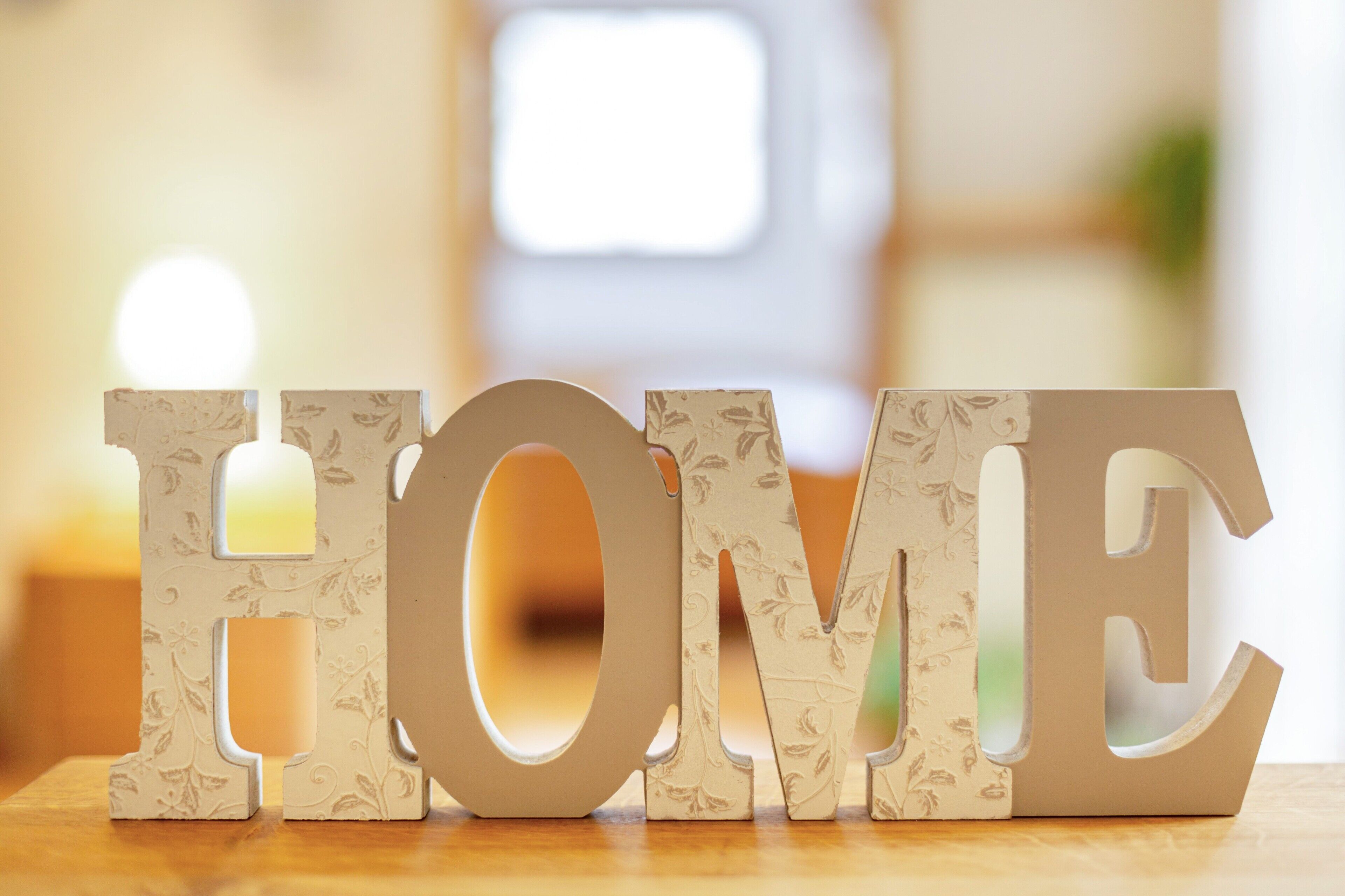 Letras de madera decorativas que deletrean 'HOME' sobre una superficie de madera.